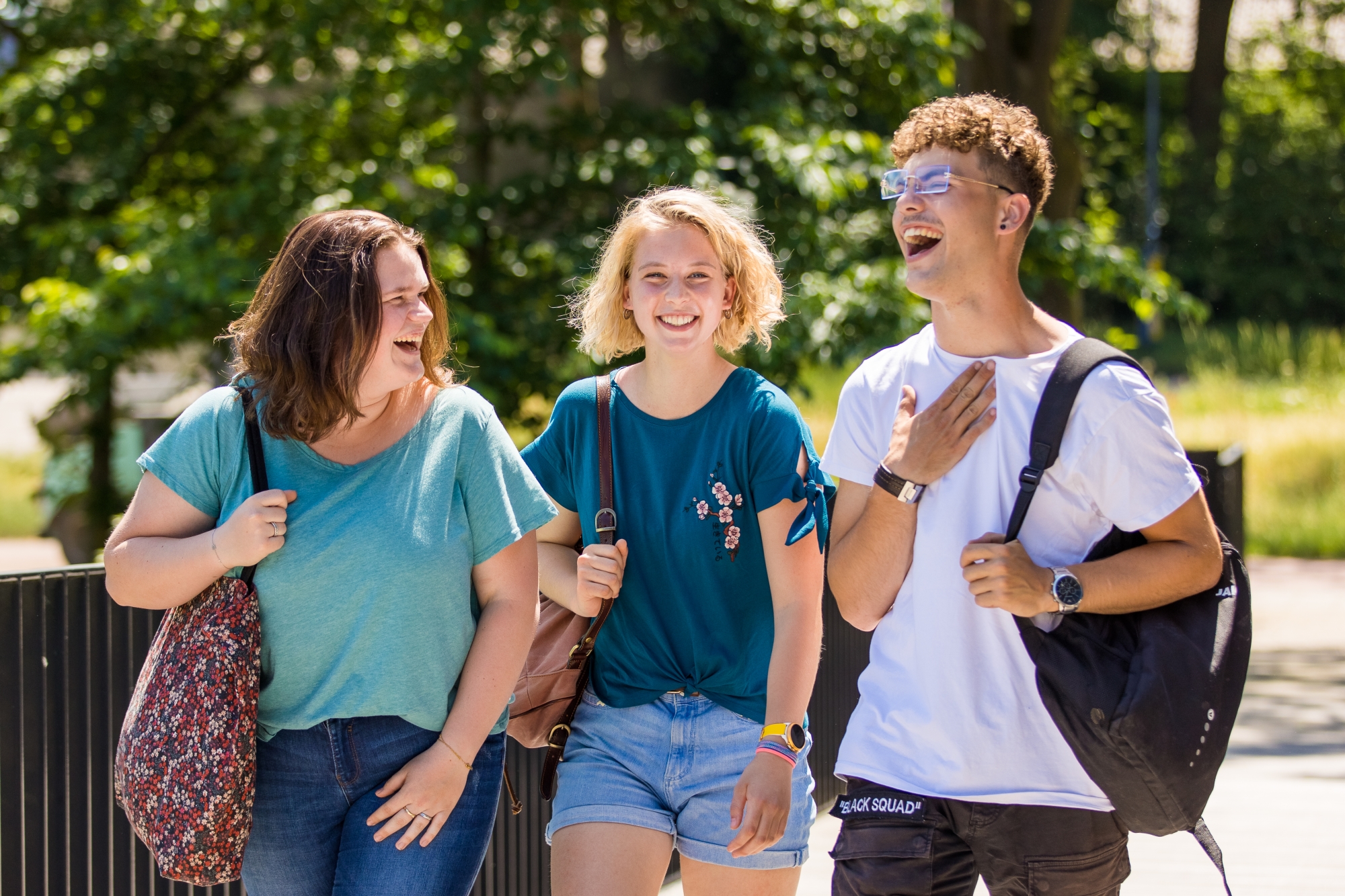 Drie lachende studenten buiten in het groen